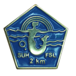 2 kilometrin uintimerkki on viisikulmainen sininen pinssi, jossa sateenkaaren alla uiva merenneito. Merkissä tekstit SUH ja FSL sekä 2 km.